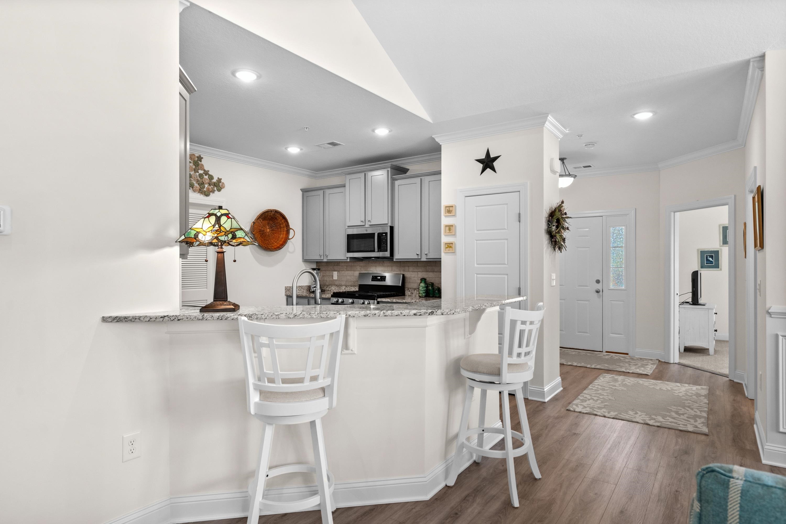 948 Jackline Place, Unit 201 Murrells Inlet, SC 29576 - Photo 14 of 37 Kitchen featuring gray cabinets, a kitchen breakfast bar, ornamental molding, light stone counters, and tasteful backsplash