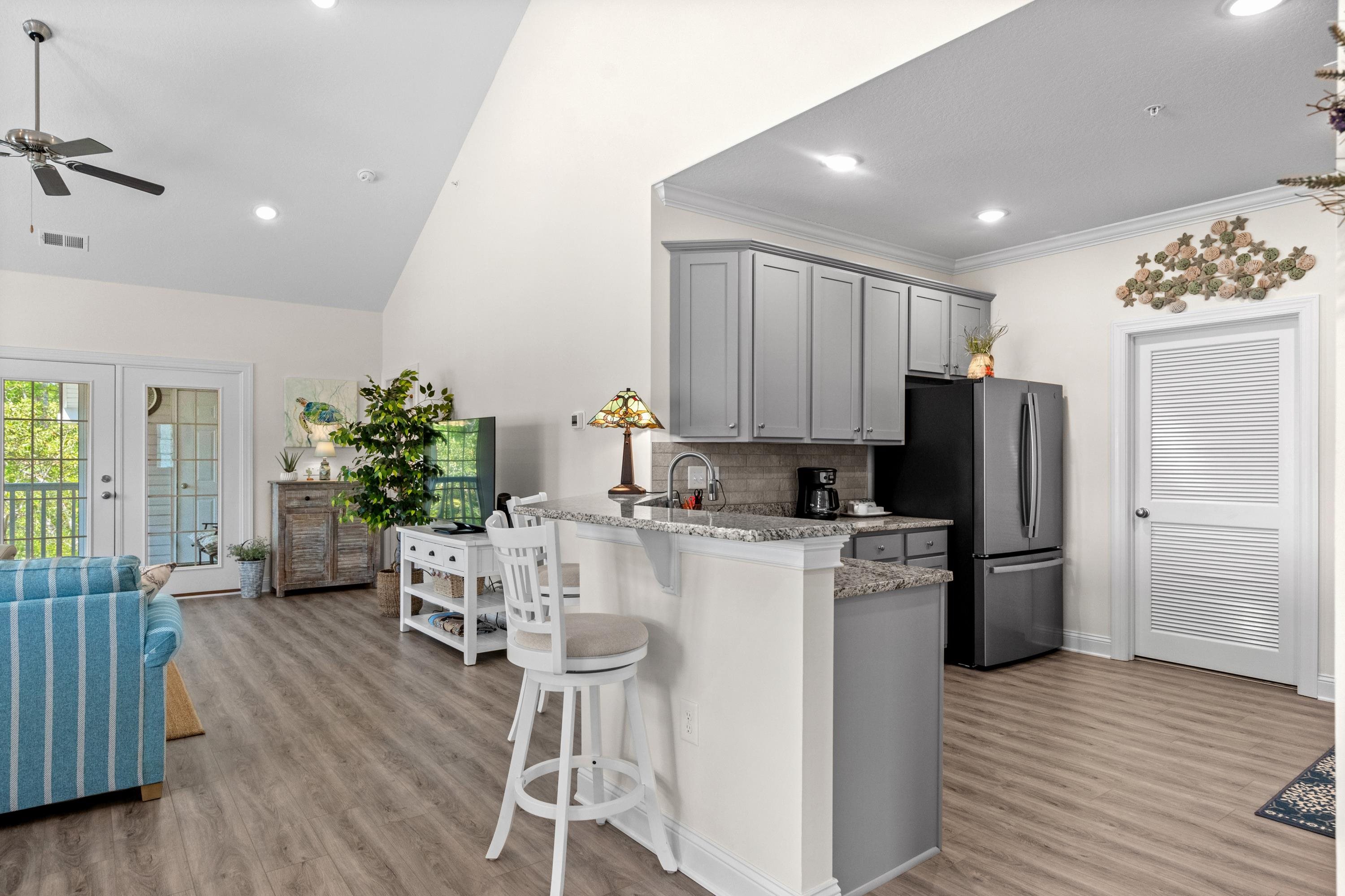 948 Jackline Place, Unit 201 Murrells Inlet, SC 29576 - Photo 37 of 37 Kitchen with gray cabinets, a breakfast bar, light stone counters, open floor plan, and freestanding refrigerator