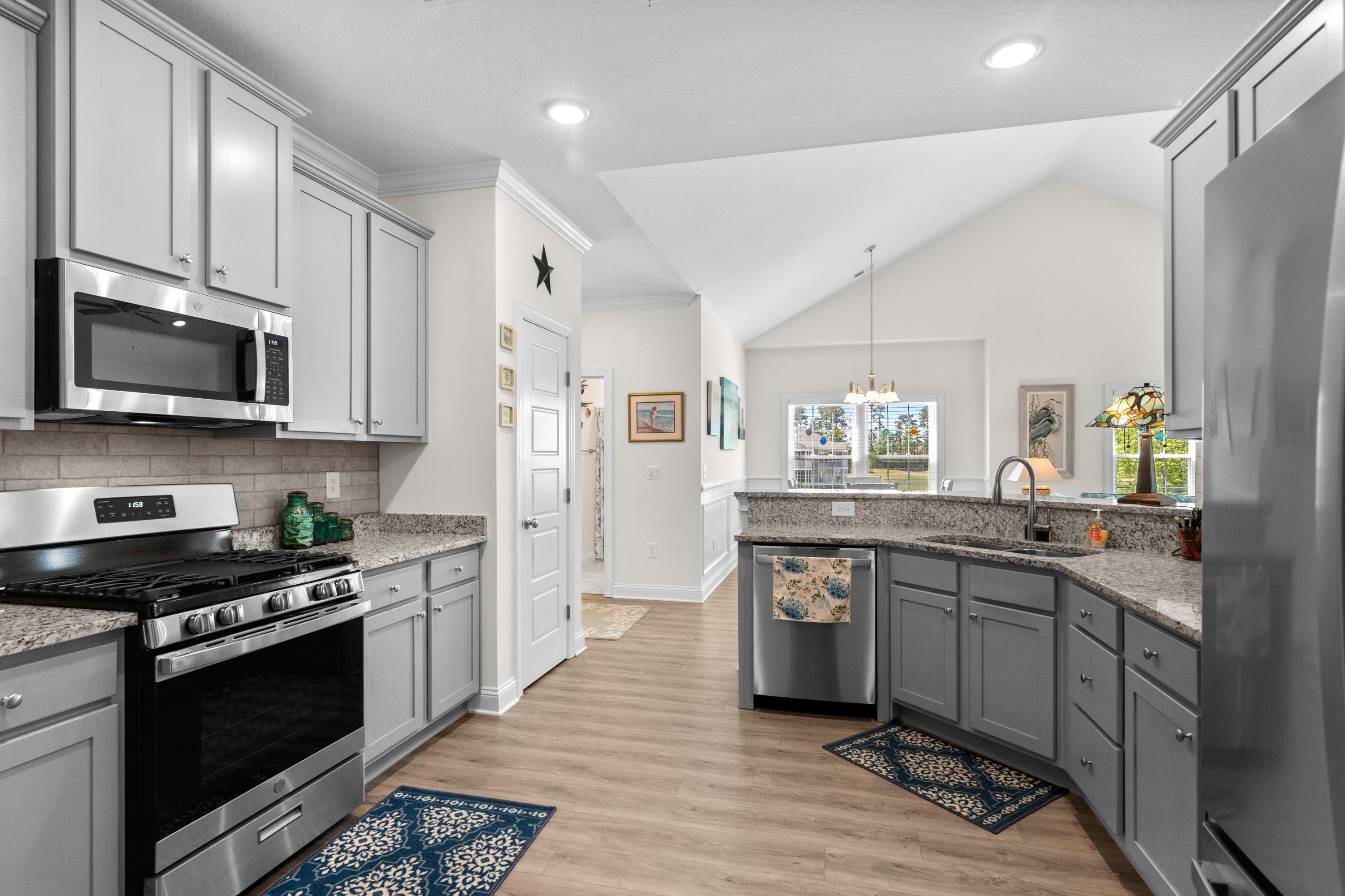 948 Jackline Place, Unit 201 Murrells Inlet, SC 29576 - Photo 17 of 37 Kitchen featuring gray cabinets, stainless steel appliances, a chandelier, light wood-style floors, and light stone countertops