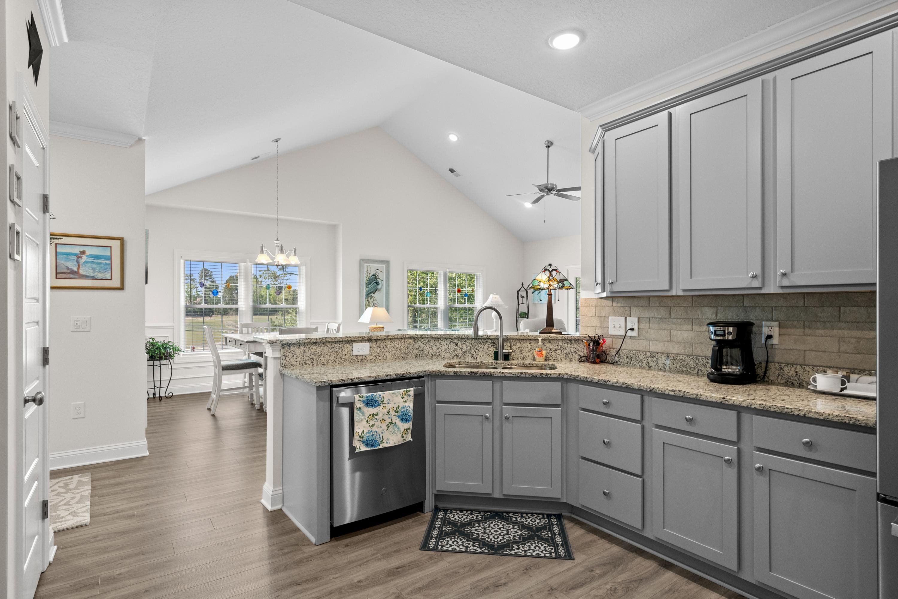 948 Jackline Place, Unit 201 Murrells Inlet, SC 29576 - Photo 18 of 37 Kitchen featuring gray cabinetry, high vaulted ceiling, light stone countertops, light wood finished floors, and stainless steel dishwasher