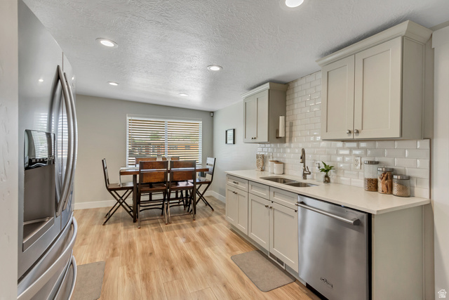 48 Moon Ridge Drive Murray, UT 84107 - Photo 9 of 30 Bright kitchen featuring white subway tile backsplash, light-colored cabinetry, stainless steel appliances, and light wood-finish flooring