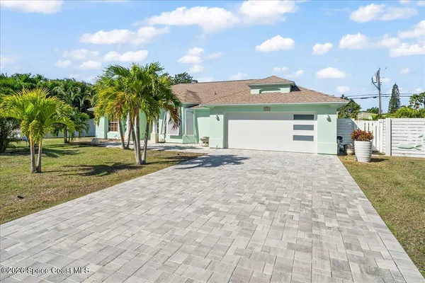 a view of a house with a yard and palm trees