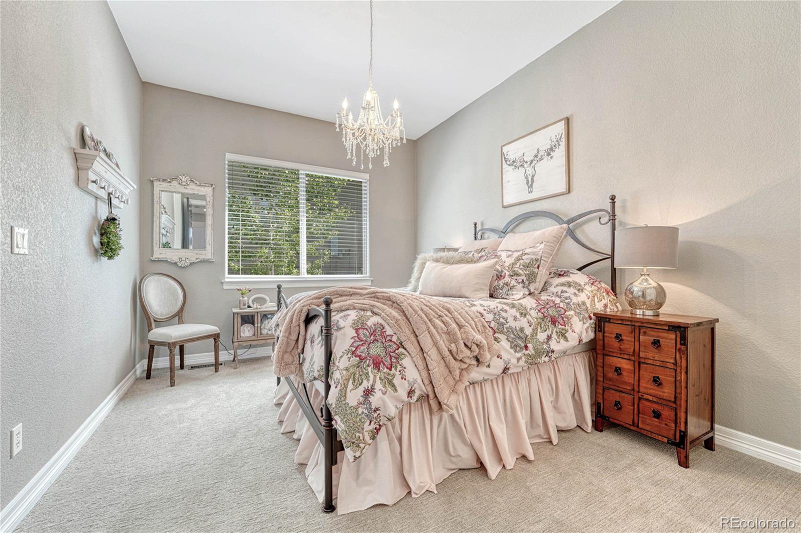 20125 East Shady Ridge Road Parker, CO 80134 - Photo 19 of 40 a bedroom with a bed and a chandelier
