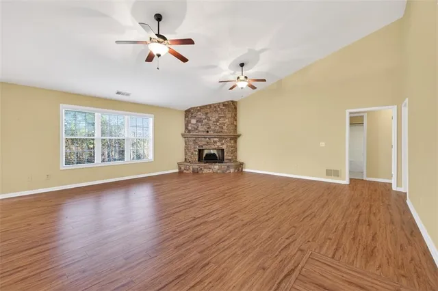 a view of an empty room with a window and wooden floor