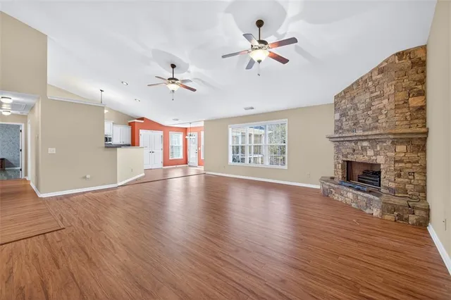 an empty room with wooden floor chandelier fan and windows