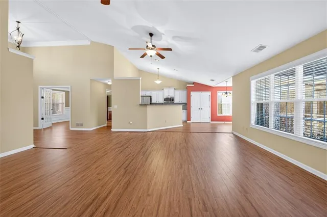 a view of an empty room with wooden floor and a window