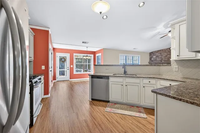 a kitchen with granite countertop a stove a sink dishwasher and a refrigerator with wooden floor