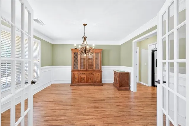 a view of a room with wooden floor chandelier and windows