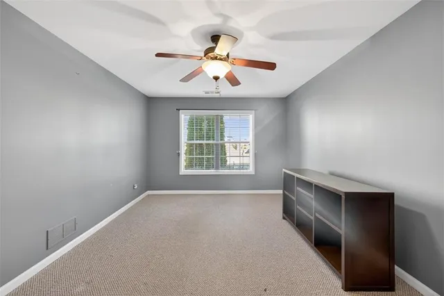 an empty room with windows and chandelier fan