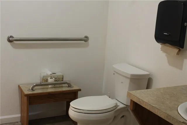 a bathroom with a granite countertop toilet and a sink