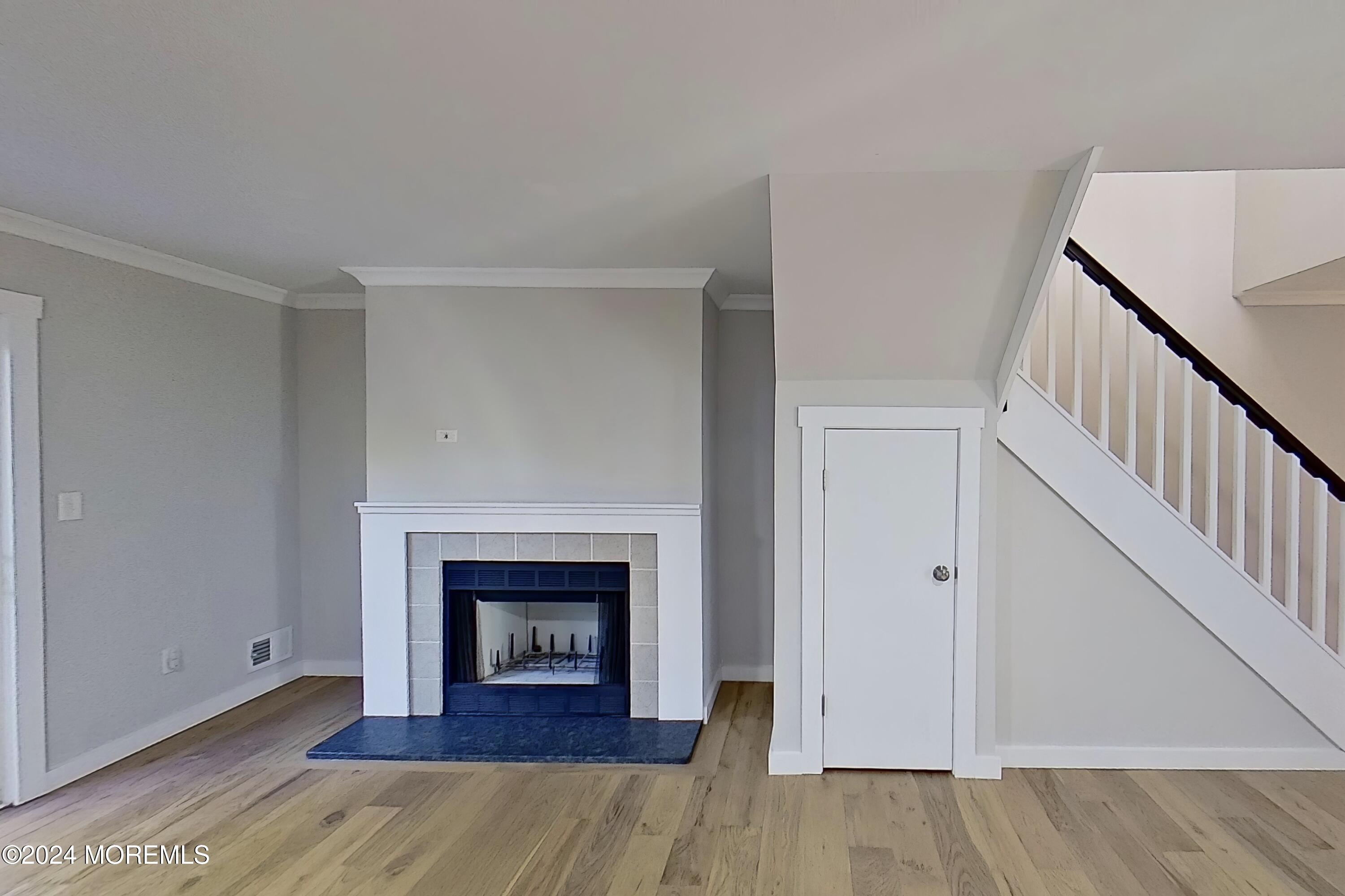 a view of an empty room with wooden floor fireplace and a window