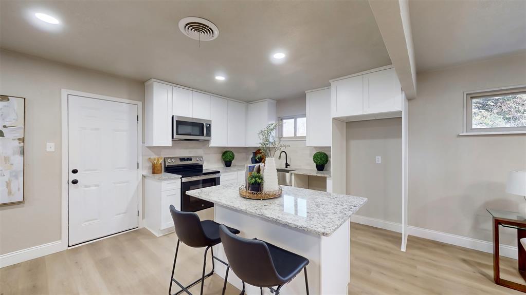 5009 Roxie Street Haltom City, TX 76117 - Photo 12 of 39 a kitchen with granite countertop cabinets stainless steel appliances a dining table and chairs