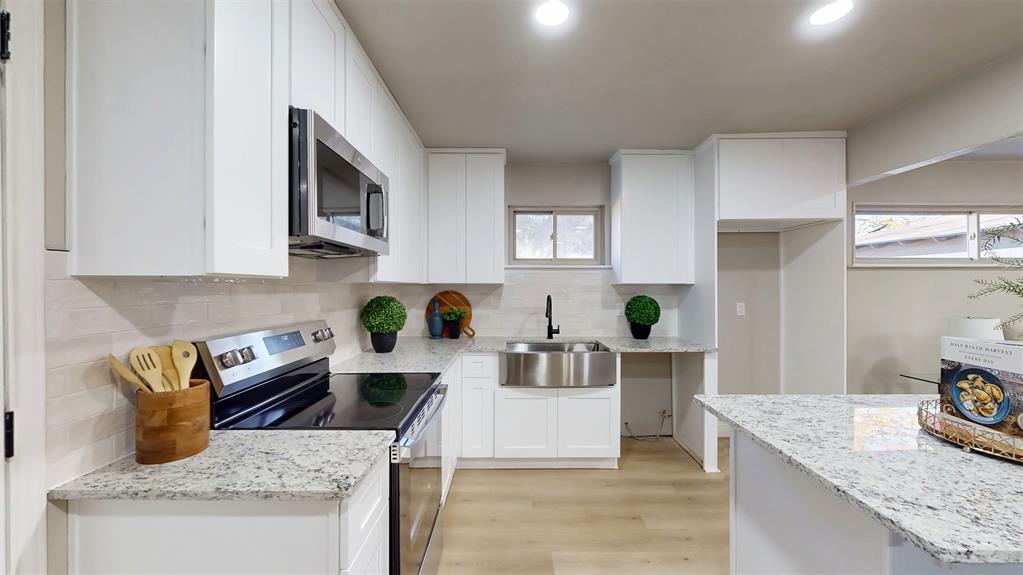 5009 Roxie Street Haltom City, TX 76117 - Photo 15 of 39 a kitchen with a stove a sink and cabinets