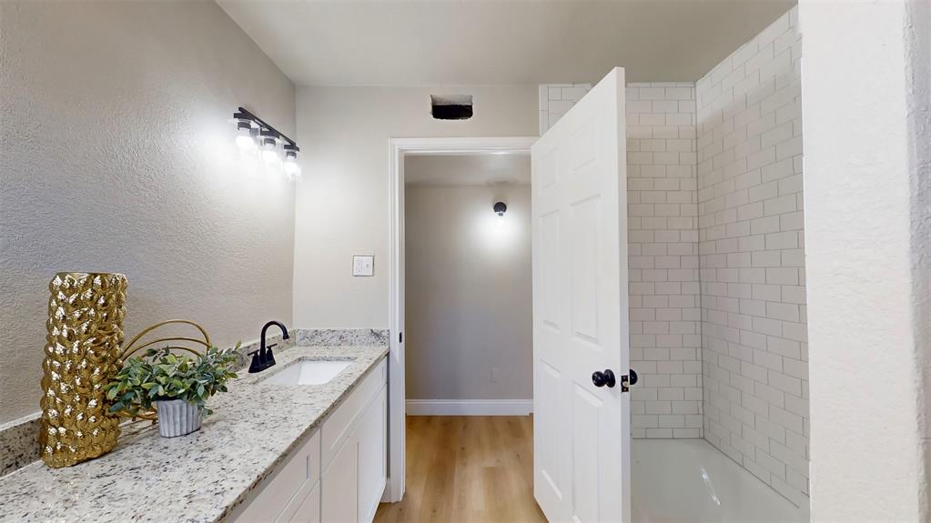5009 Roxie Street Haltom City, TX 76117 - Photo 23 of 39 a bathroom with a granite countertop sink a mirror and shower