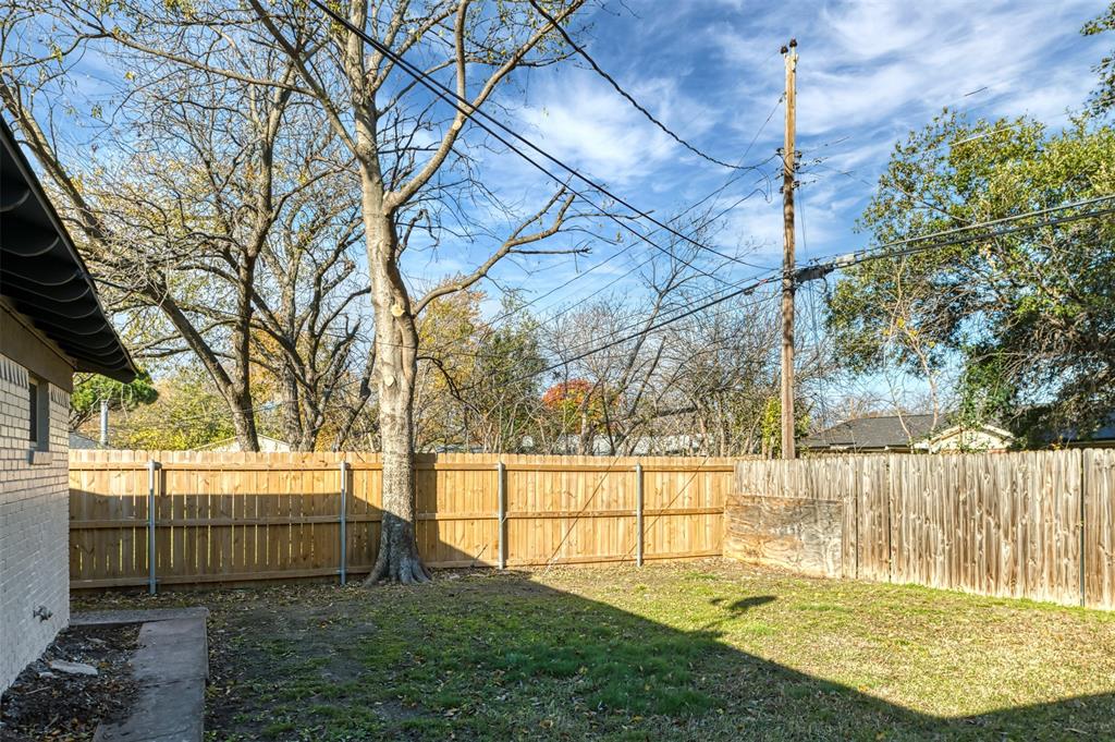 5009 Roxie Street Haltom City, TX 76117 - Photo 37 of 39 a view of a backyard with large trees and a wooden fence
