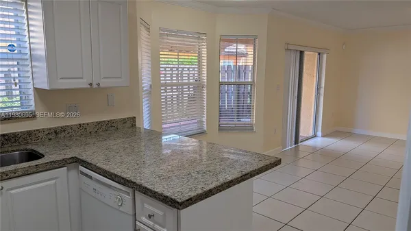 a kitchen with granite countertop a sink window and cabinets