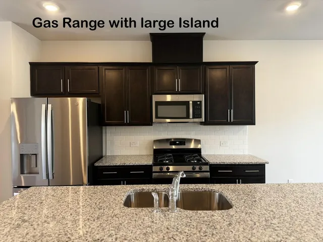 a kitchen with stainless steel appliances granite countertop a sink a stove a microwave and a refrigerator