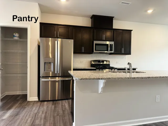a kitchen with granite countertop a refrigerator and a stove top oven