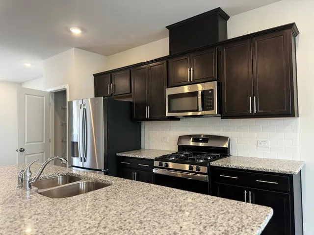 a kitchen with granite countertop wooden cabinets and black stainless steel appliances