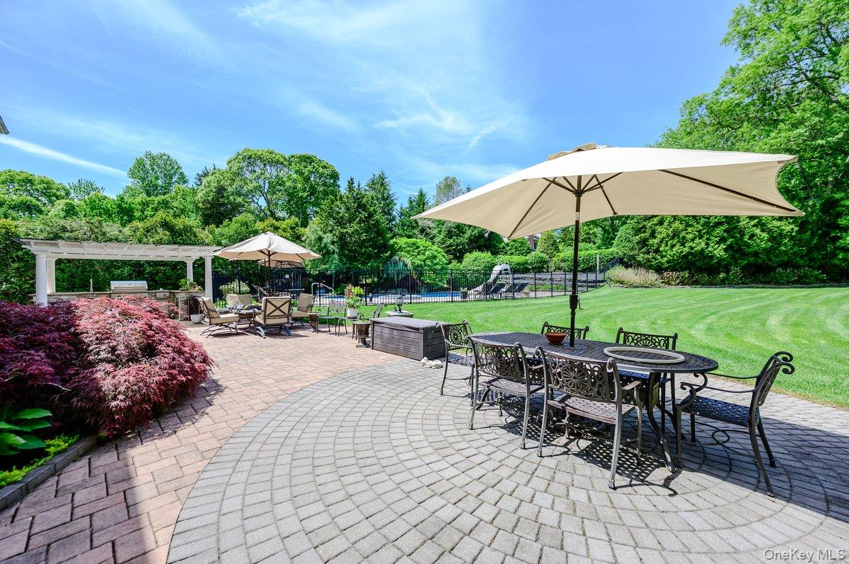 129 Round Swamp Road Huntington, NY 11743 - Photo 41 of 49 Expansive paver patio featuring a circular pattern, an integrated outdoor kitchen with a built-in grill, and a white pergola
