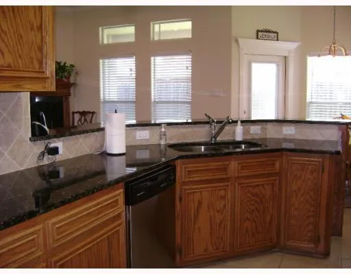 a kitchen with granite countertop a sink a window and cabinets