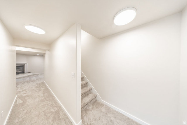 2169 Orchard Pines Loop East Bountiful, UT 84010 - Photo 22 of 32 Carpeted stairs leading to a lower level featuring recessed lighting, a fireplace with a mantel, and light-colored walls and carpeting