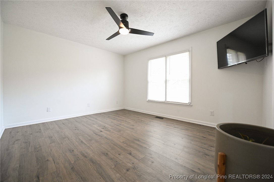 5057 Summer Ridge Road Fayetteville, NC 28303 - Photo 18 of 29 an empty room with wooden floor fan and windows
