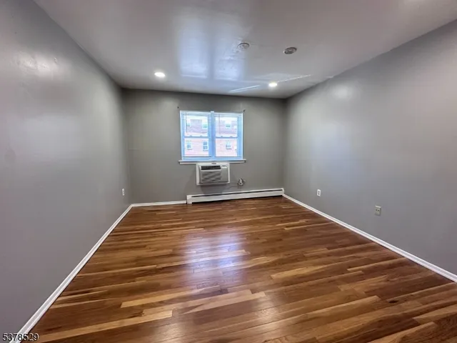 a view of empty room with wooden floor