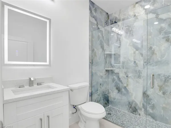 a bathroom with a sink vanity mirror and toilet