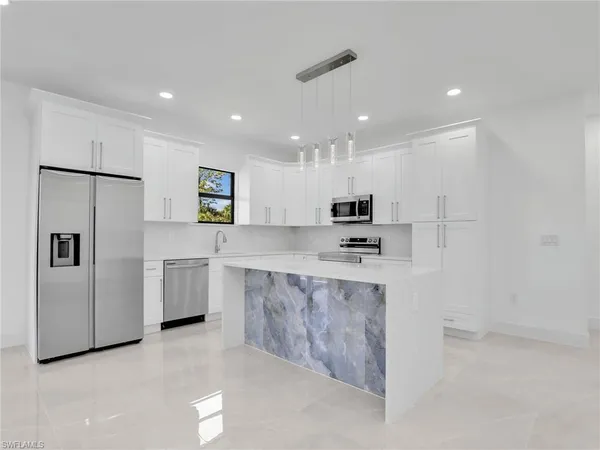 a large kitchen with stainless steel appliances a refrigerator a sink dishwasher with a stove and white cabinets