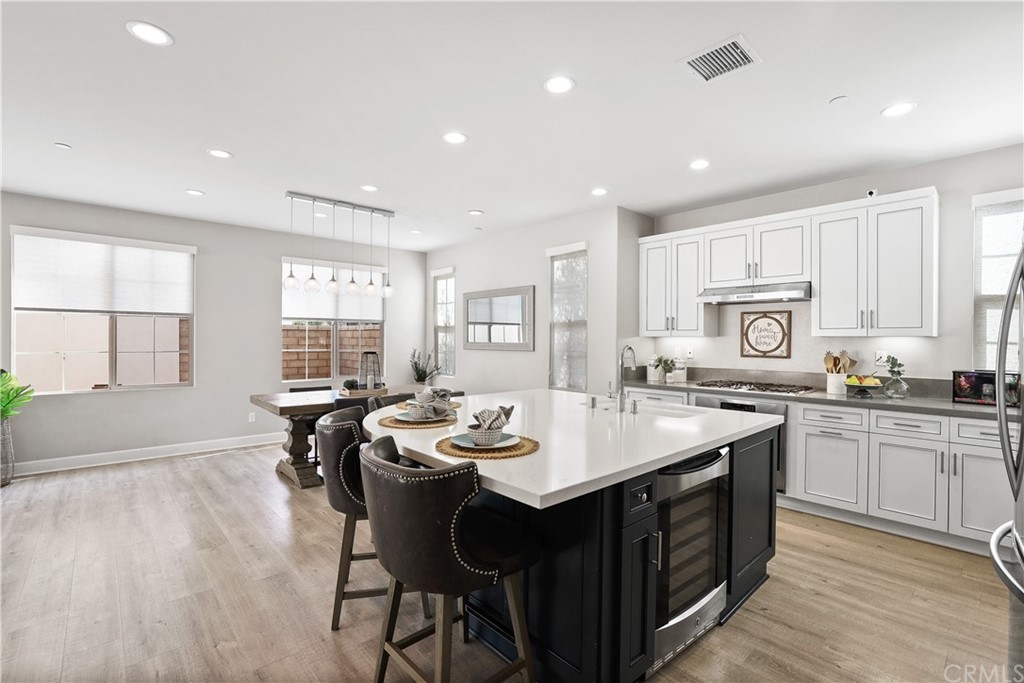 26 Lilac Lake Forest, CA 92630 - Photo 3 of 52 a kitchen with a stove a sink dishwasher and a dining table with wooden floor