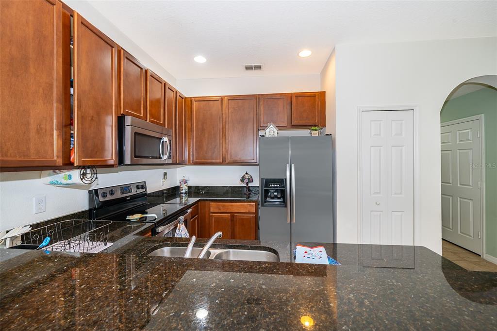 4113 Hedge Maple Place Winter Springs, FL 32708 - Photo 7 of 31 a kitchen with stainless steel appliances granite countertop a refrigerator a stove and a sink with wooden cabinets