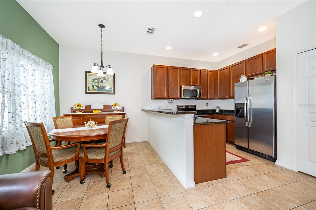 4113 Hedge Maple Place Winter Springs, FL 32708 - Photo 9 of 31 a dining table chairs and a refrigerator in a kitchen
