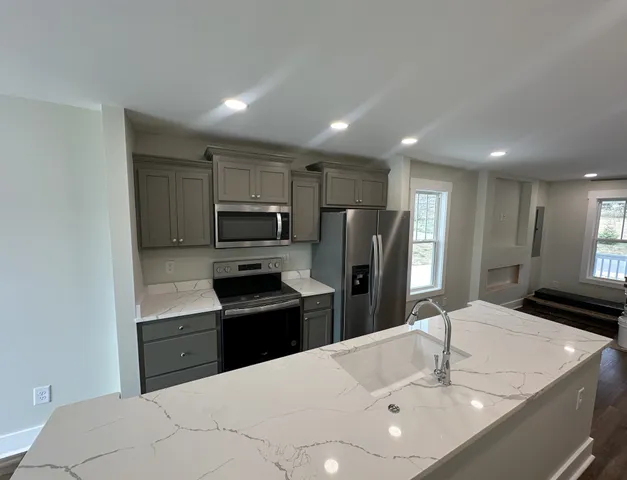 a large kitchen with a sink and wooden floor