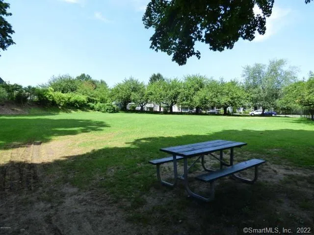 a wooden bench sitting in the grass near a big yard