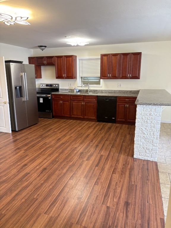 7220 Avenue R Galveston, TX 77551 - Photo 4 of 8 a kitchen with stainless steel appliances kitchen island granite countertop wooden floors a stove top oven a sink and dishwasher