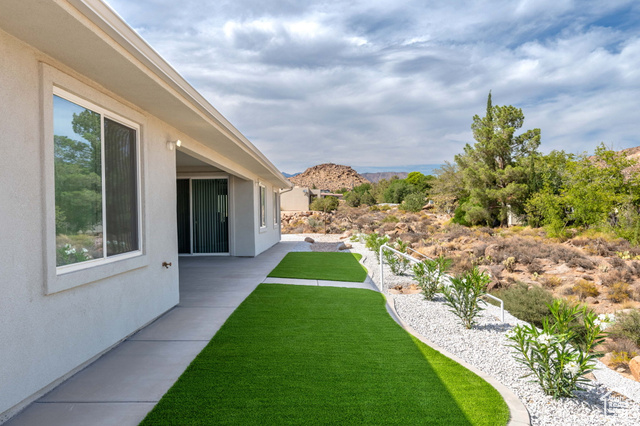 230 Boulder Way Leeds, UT 84746 - Photo 49 of 72 View of grassy artificial turf yard featuring a patio area & natural terrain. Concrete sidewalks surround the home.