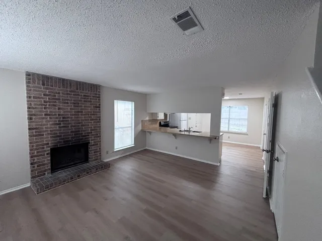 an empty room with wooden floor fireplace and windows