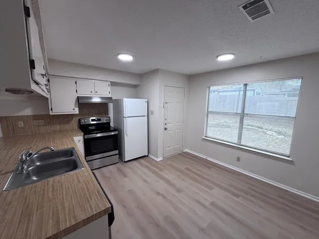 a kitchen with granite countertop a refrigerator stove and sink