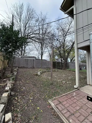 a view of a backyard with large trees and wooden fence