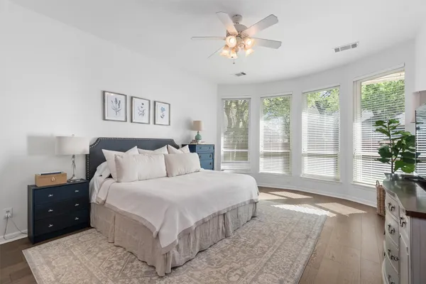 a spacious bedroom with a large bed and a chandelier fan
