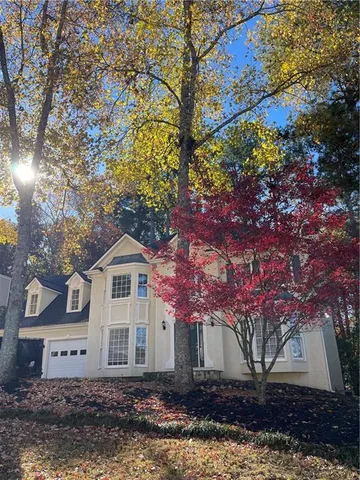 a front view of a house with a yard and large trees