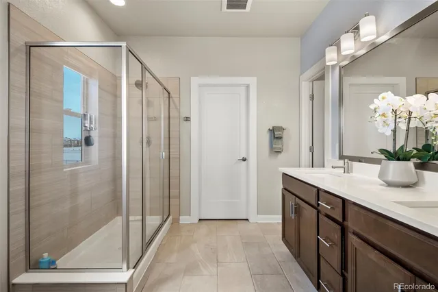 a spacious bathroom with a granite countertop sink a mirror and a shower