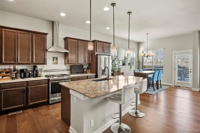 a kitchen with stainless steel appliances granite countertop a stove refrigerator and a view of living room