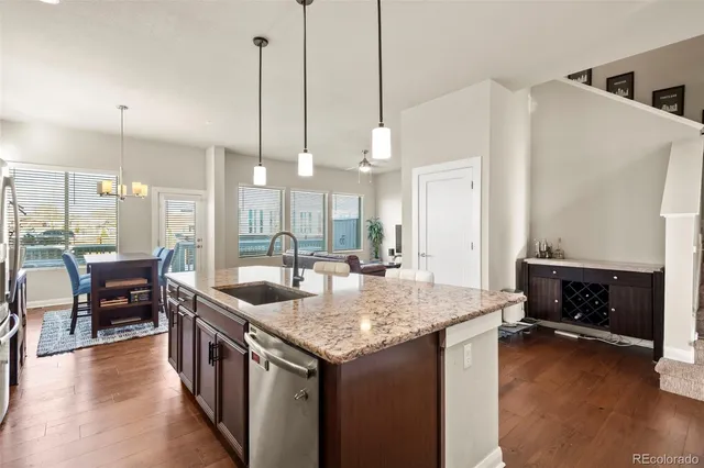 a kitchen with a stove kitchen island and couches wooden floor