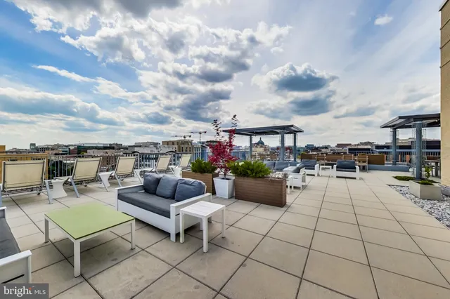 a view of roof deck with couches and potted plants
