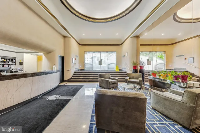 a living room with stainless steel appliances furniture a rug and a large window