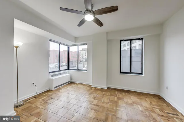 a view of an empty room with window and chandelier fan