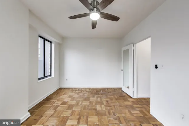 a view of an empty room and window and chandelier fan