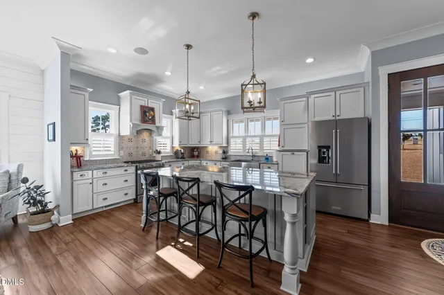 a kitchen with stainless steel appliances granite countertop a sink a stove and a wooden floors